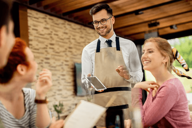 A server greeting guests with a tablet
