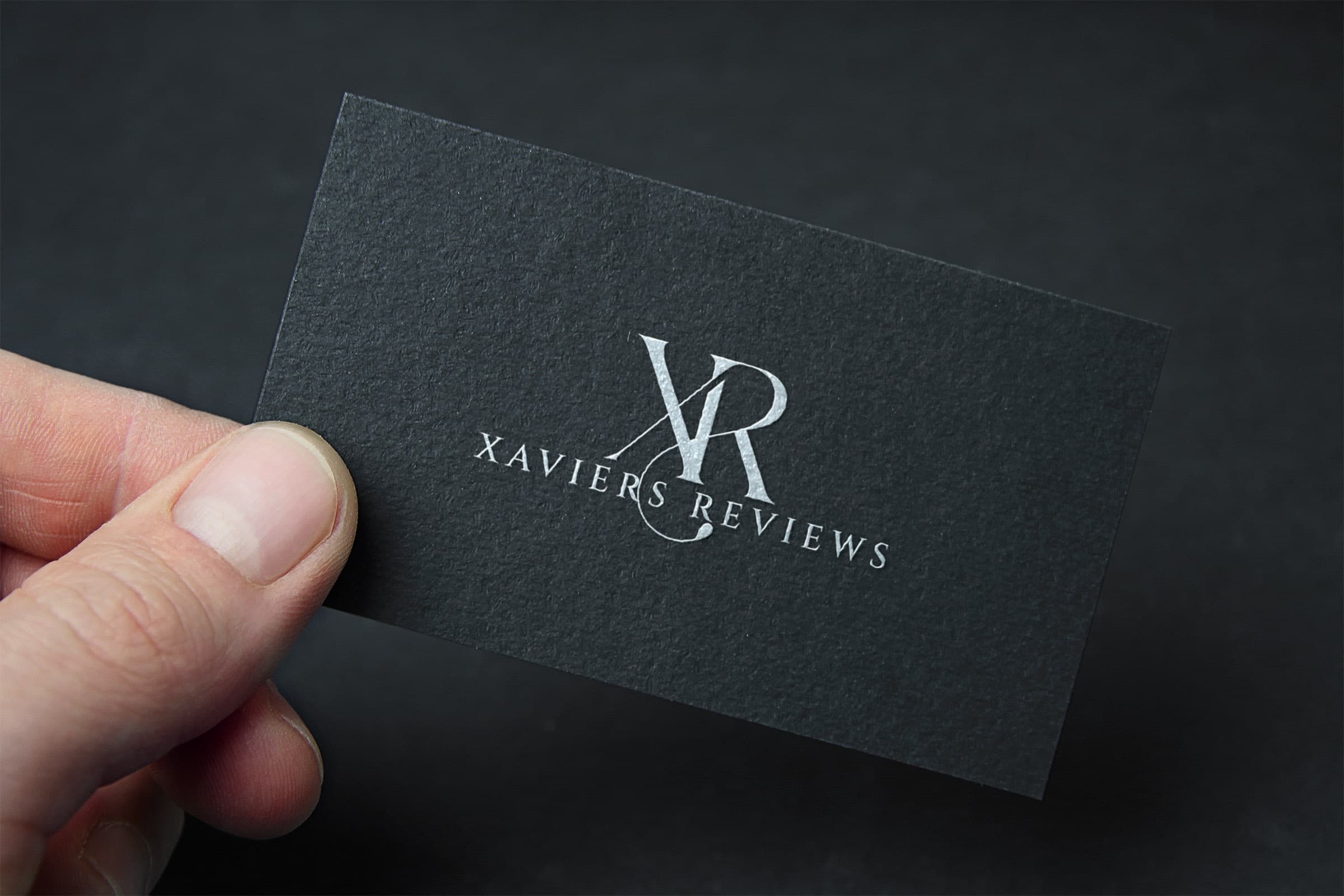 A hand holding a Xaviers Reviews business card